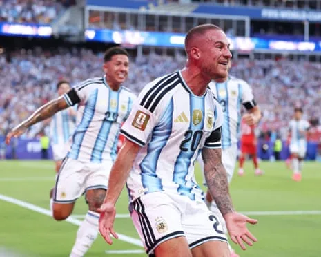 Alexis Mac Allister in Argentina's striped jersey celebrates with arms outstretched, mouth open in joy